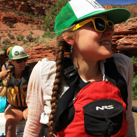 Women wearing sunglasses and a hat while boating on a river