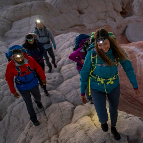 a group of hikers walking with headlamps in the desert