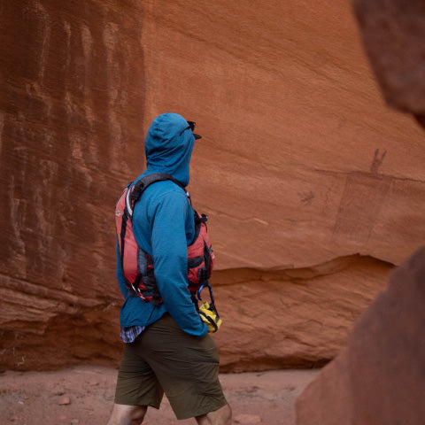 man wearing a jacket while hiking in a desert canyon