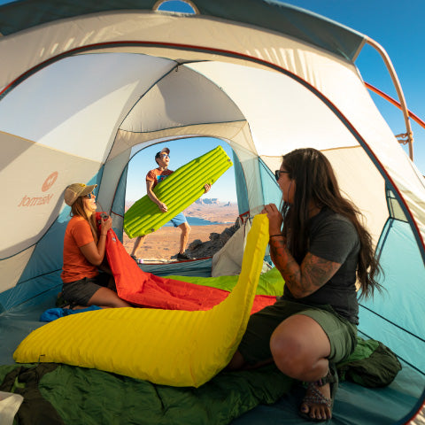 campers in a tent blowing up their sleeping pads