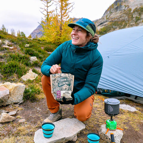 a hiker eating a backpacking meal in the mountains