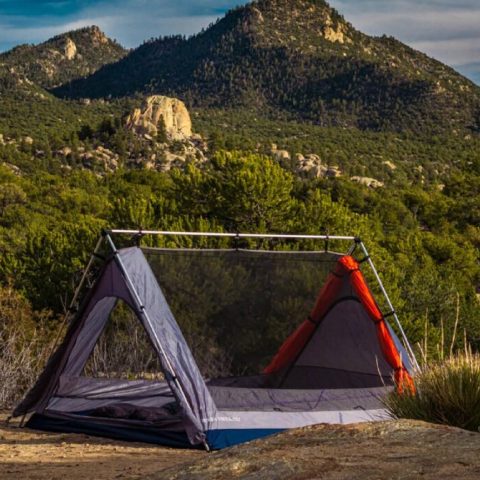 Tent sitting near rocks with a mountain backdrop 
