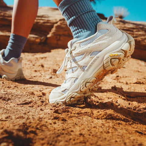 close up view of a persons feet wearing hiking shoes on red sandstone