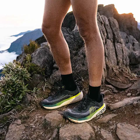 close up view of a person wearing trail running shoes in the mountains