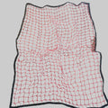 A square black mesh safety net with bright pink cord lines, laid flat on a gray carpeted floor.