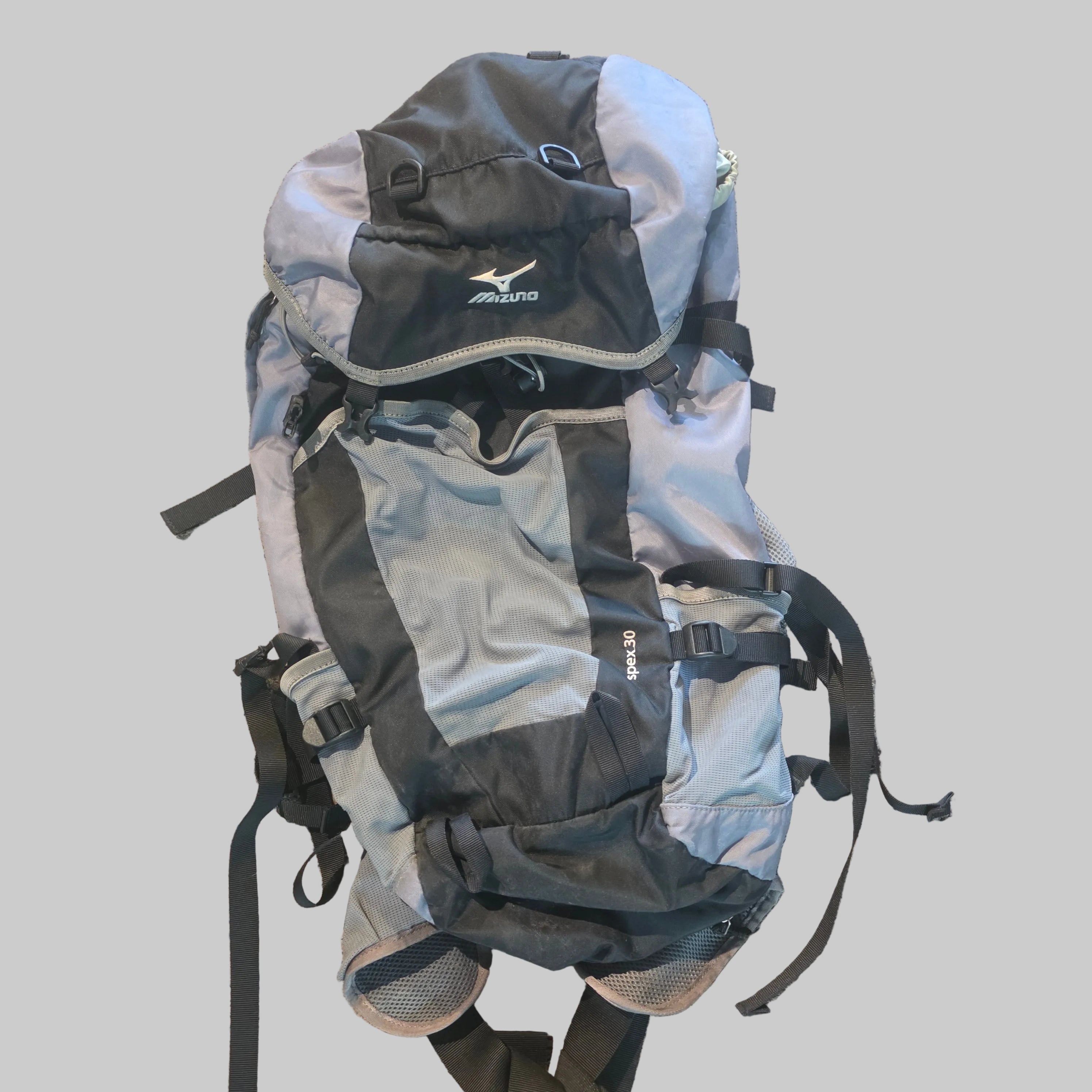 A Mizuno hiking backpack in gray and black, laid flat on a textured beige carpet.