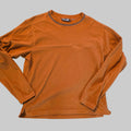 An orange long-sleeve crewneck shirt with a horizontal seam across the chest and a gray ribbed collar, laid flat on a gray carpeted floor.