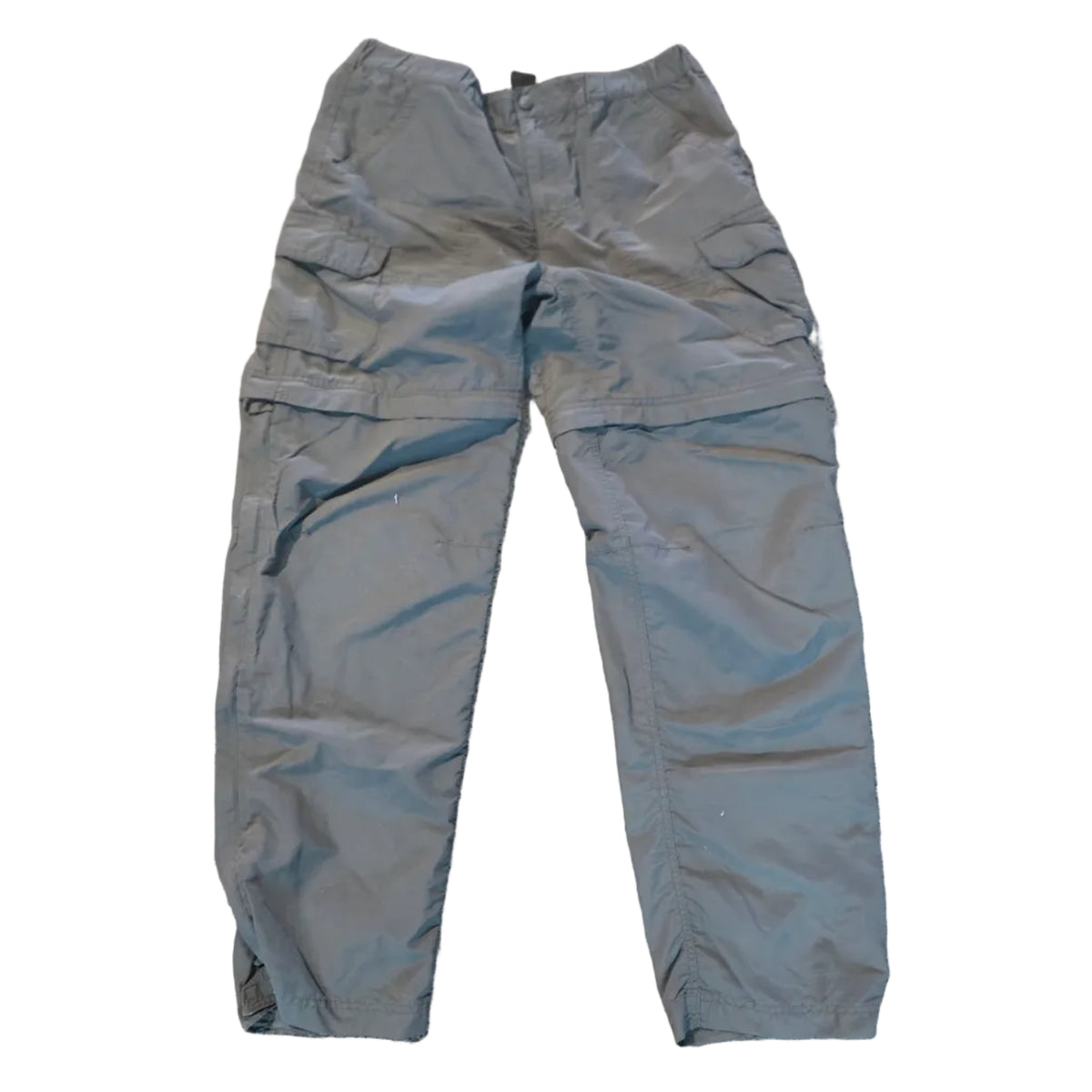 A pair of gray convertible pants laid flat on a beige carpeted floor.