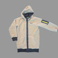 A fleece hooded jacket laid flat on a textured gray carpet. The jacket is cream-colored with dark navy cuffs, hem, and front zipper, featuring a yellow reflective strip on the left sleeve.