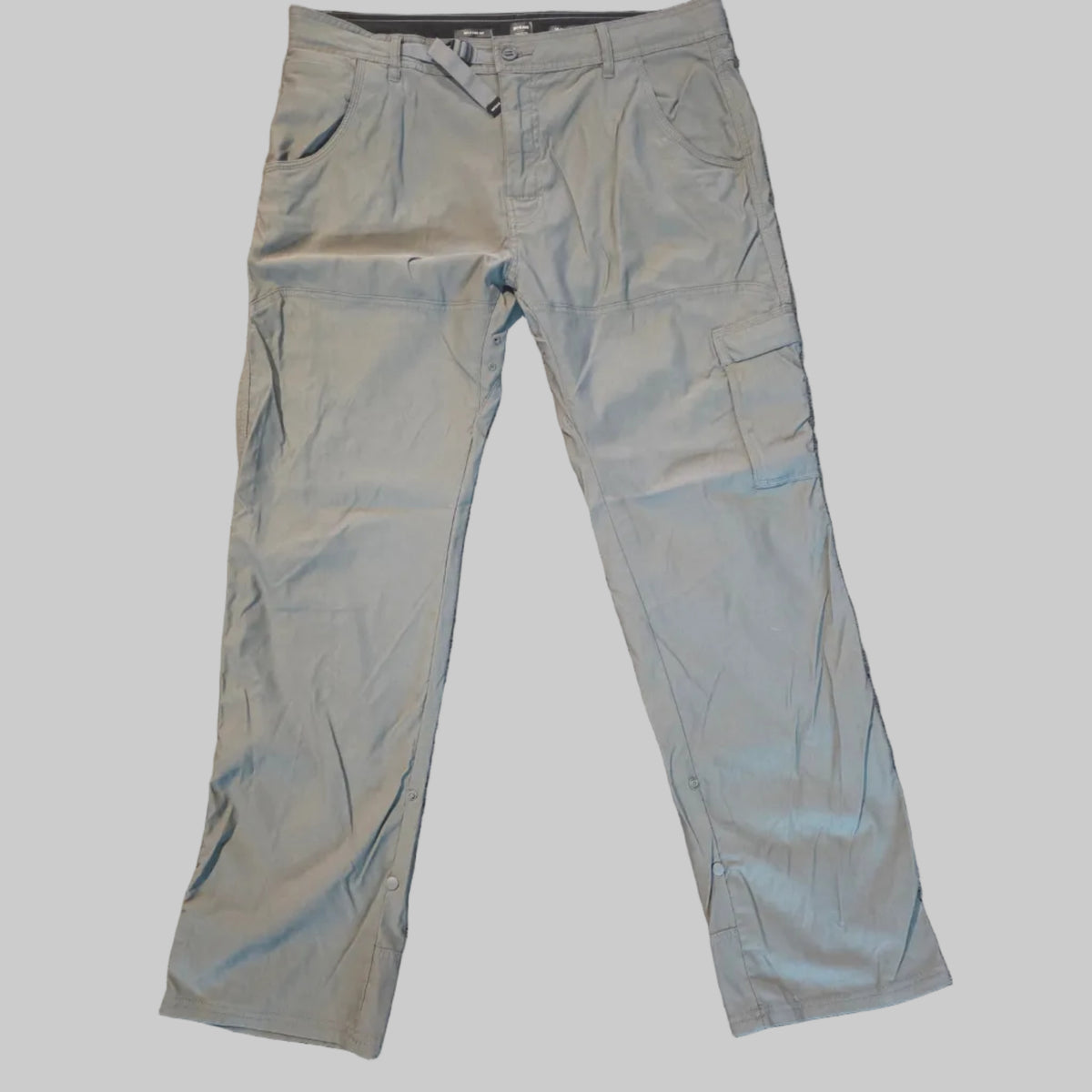 A pair of light gray cargo pants laid flat on a textured beige carpet.