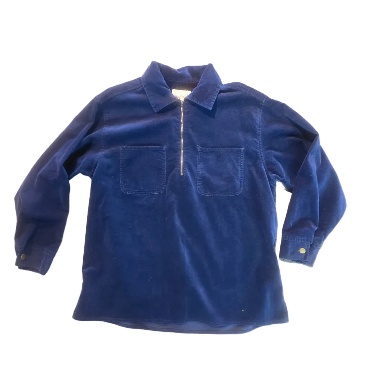 A dark blue corduroy long-sleeve button-up shirt laid flat on a beige carpeted floor.