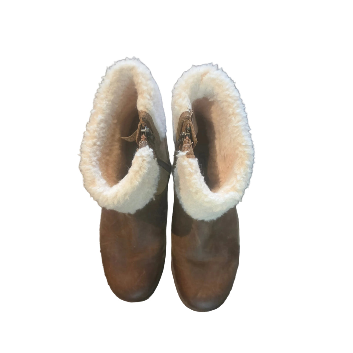 A pair of brown leather ankle boots with thick white shearling-style lining, photographed from above on a textured gray carpet.