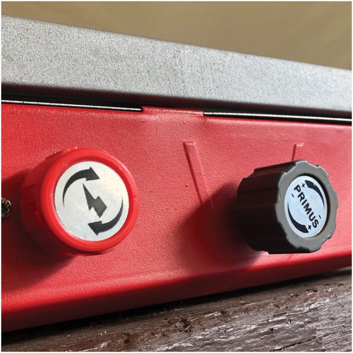 Close-up of a red machine control panel with a red circular switch and a black adjustment knob labeled PRIMIS.