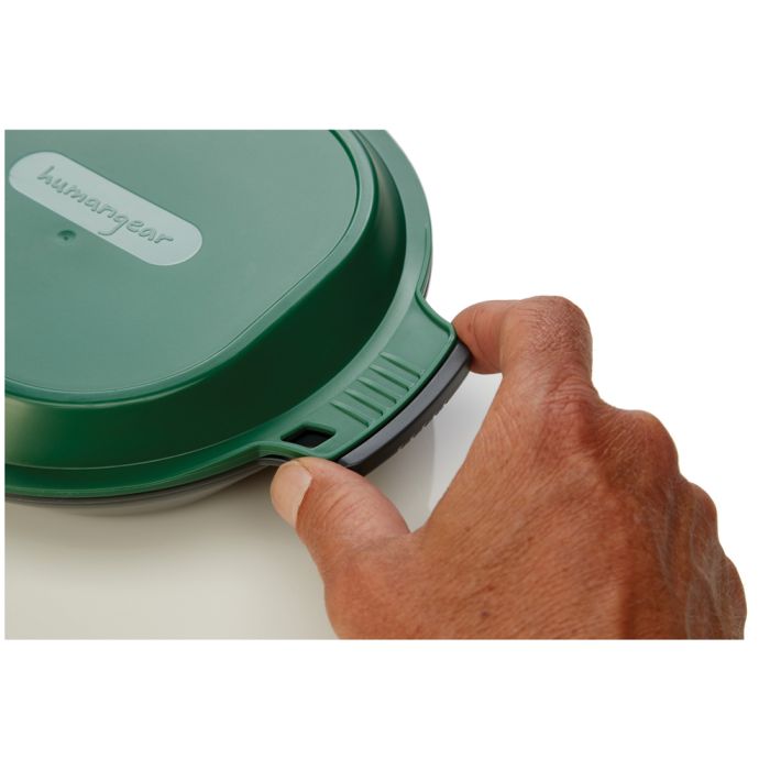 A close-up of a hand pressing a green Humagear device against a white surface, demonstrating its flexible seal.