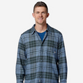 A man wearing a blue and green plaid button-down shirt over a dark blue t-shirt and dark pants, standing against a light gray background.