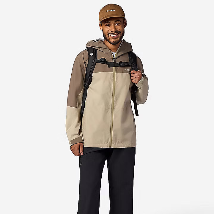 Man wearing a beige and brown jacket with a backpack on a white background