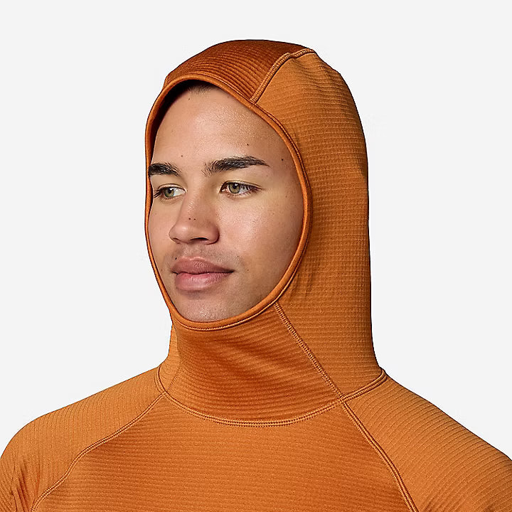 A man wearing a textured orange hooded long-sleeve top against a light gray background.