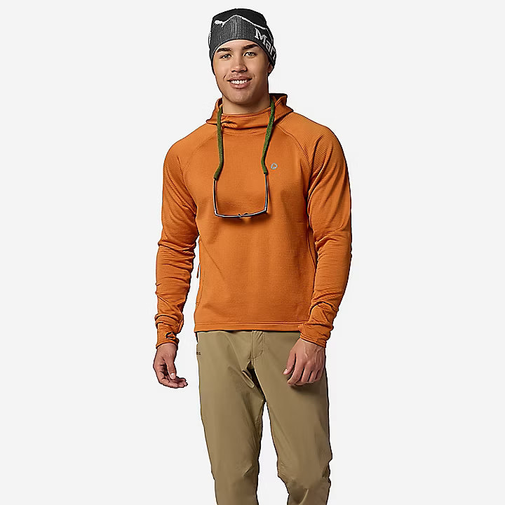 A man modeling an orange hooded long-sleeve shirt, khaki pants, and a black beanie against a light gray studio background.
