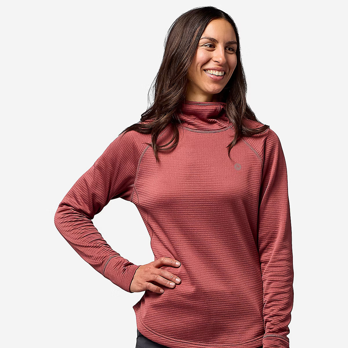 A woman wearing a ribbed, long-sleeve cowl-neck athletic top in a dusty rose color, paired with dark gray pants, against a plain light gray background.