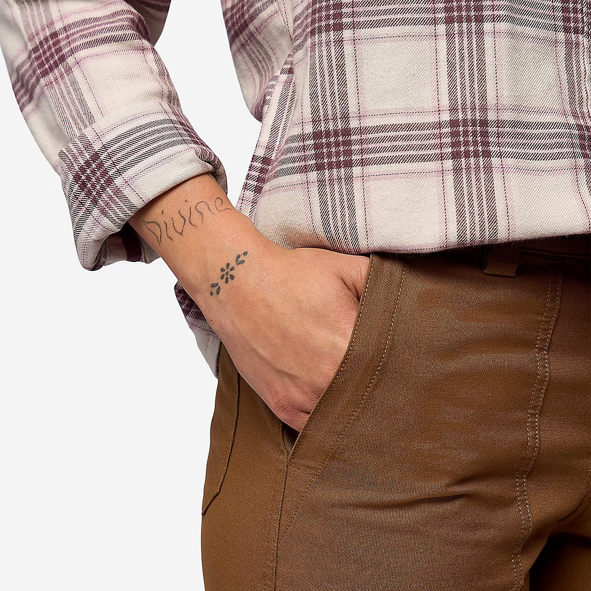 Close-up of a person wearing brown pants and a cream plaid shirt, with the hand in the pocket of the pants.
